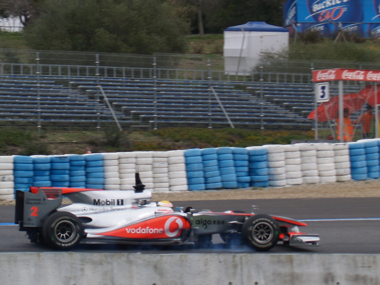 a man in grey and orange racing car making a turn