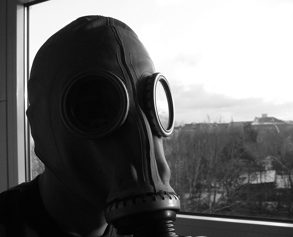 man in a gas mask and protective mask standing by window