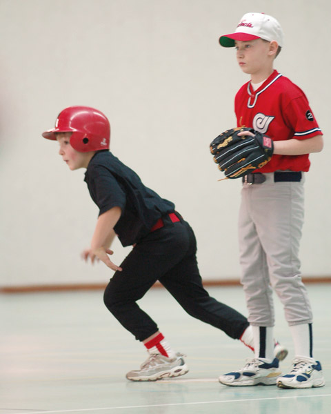 a boy in red hat playing base ball with another boy