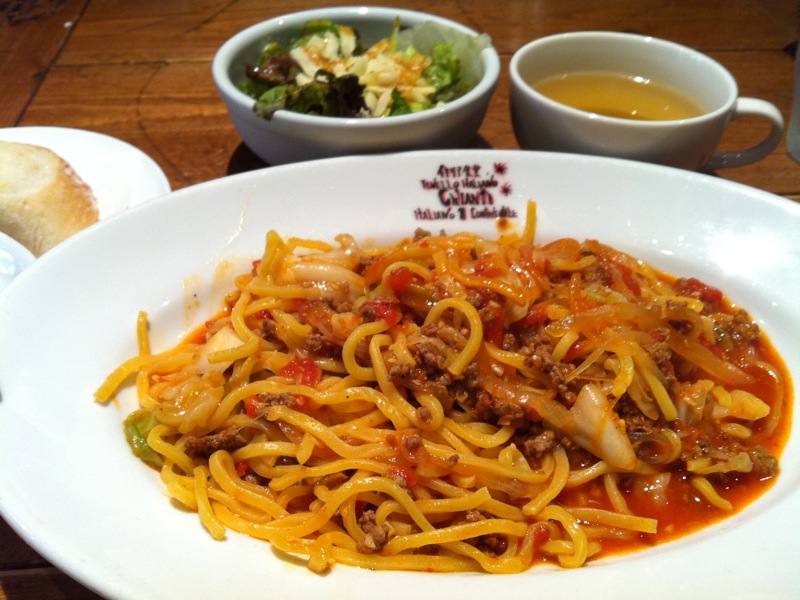 spaghetti, salad, and meat in bowls sit on a table