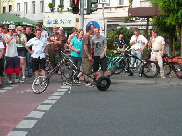 several people watch and observe as a bicycle pulls a car