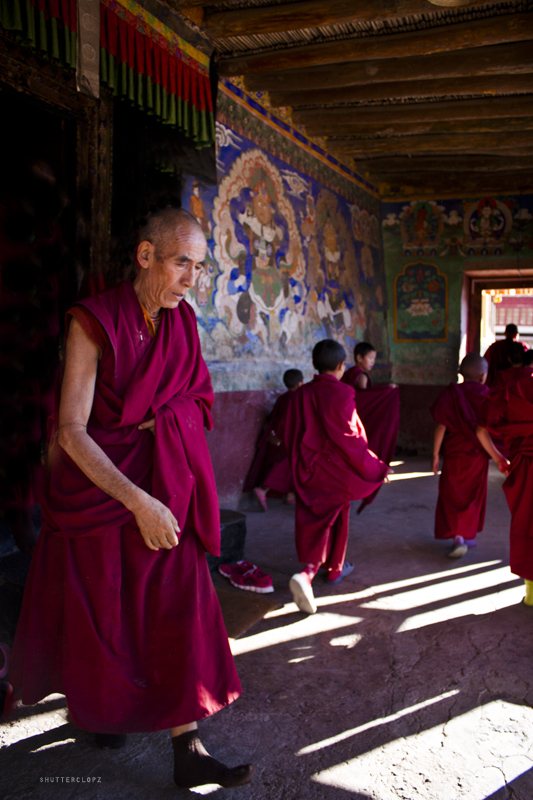 the monk is walking through a doorway with people dressed in red