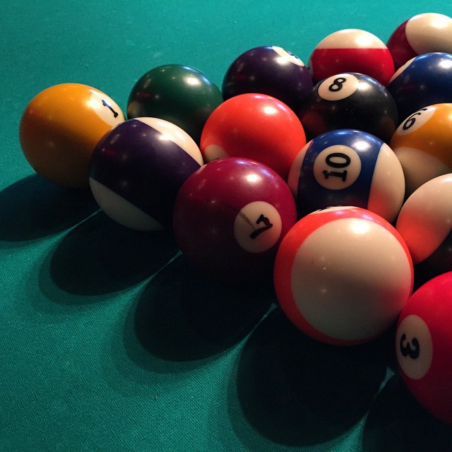 billiards balls scattered out on a green table