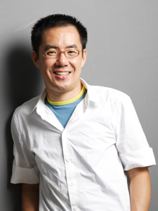 an asian man standing against a grey background in front of a gray wall
