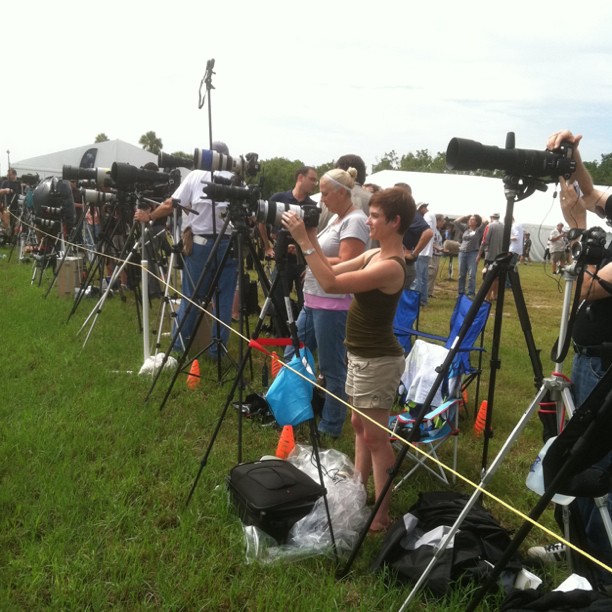 a woman holding a camera and standing by a group of people in grassy field