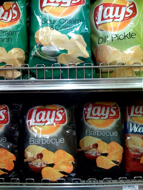 a vending shelf filled with lays potato chips and dips