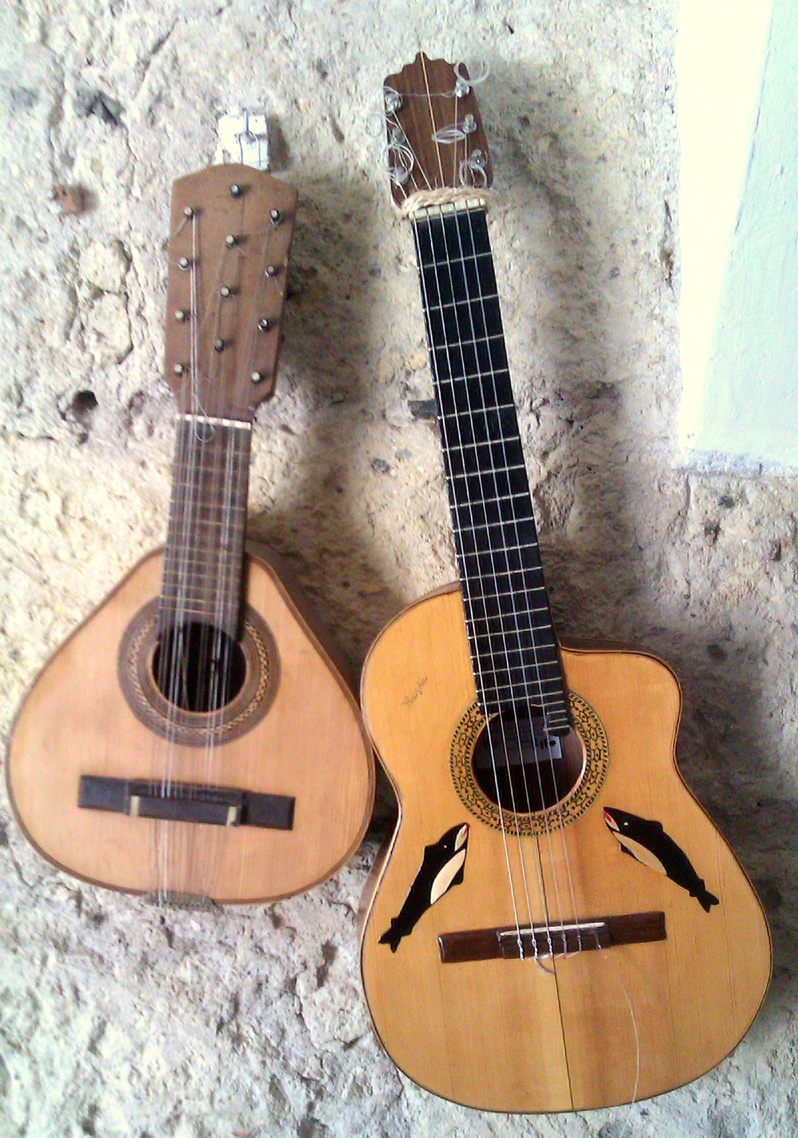two guitars made from wood, one has a guitar strings on it
