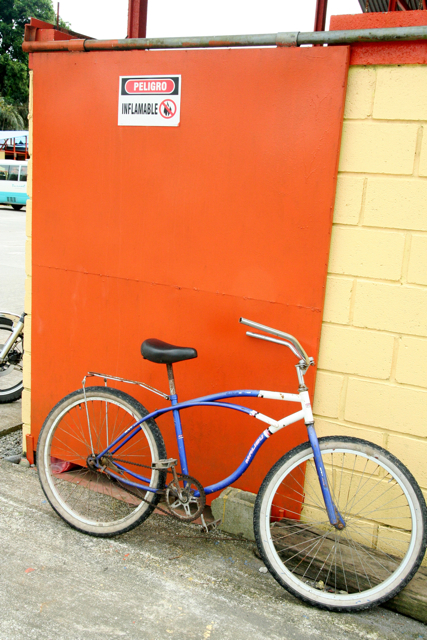 an orange wall and a blue bike parked on the sidewalk