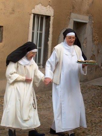 two women dressed in religious robes walking in the dirt