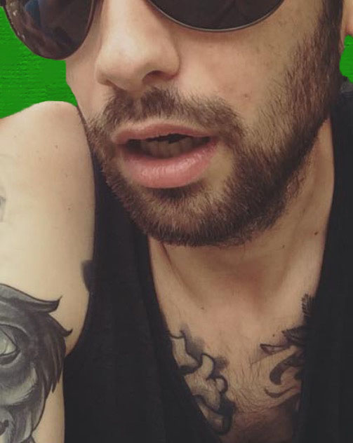 a man with dark eyeliners and a tattoo looks off to his right