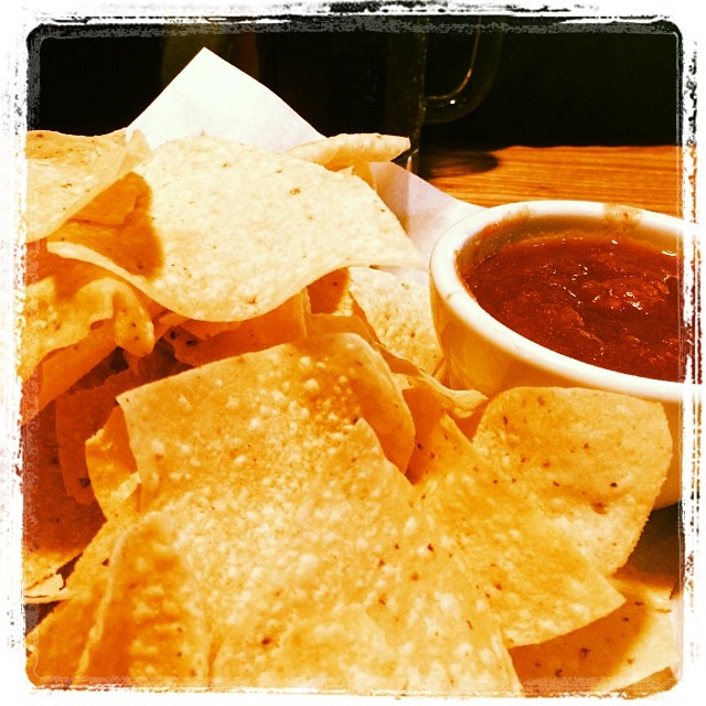 a plate of tortilla chips and salsa on a wooden table