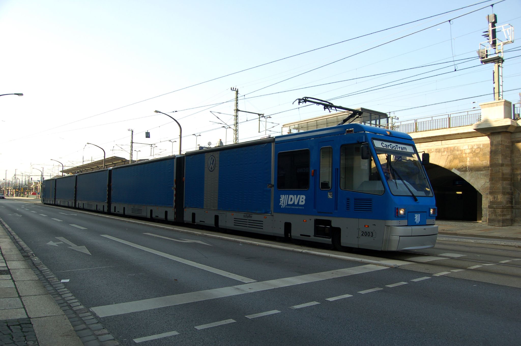 blue train with red doors passing under overhead wires