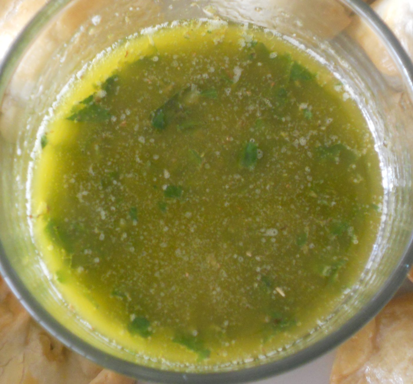 a glass filled with green liquid next to chips