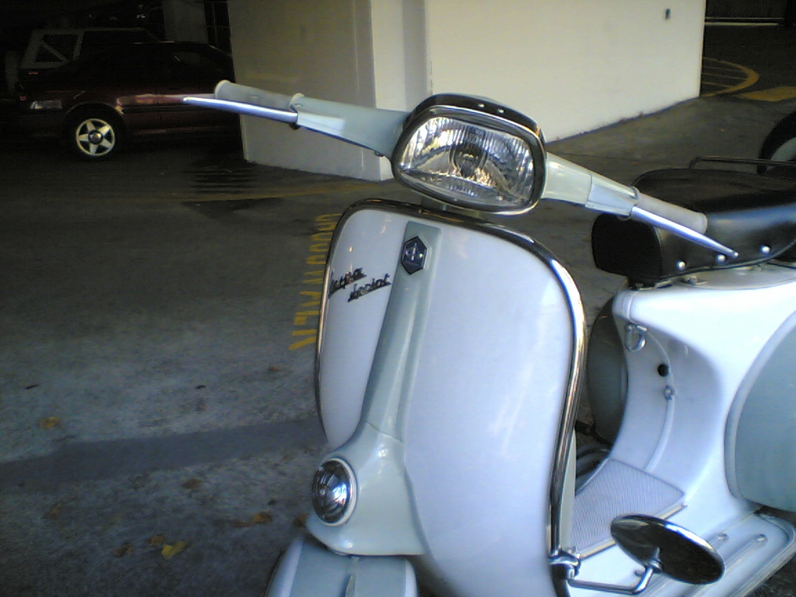 a white scooter parked in a garage next to a wall