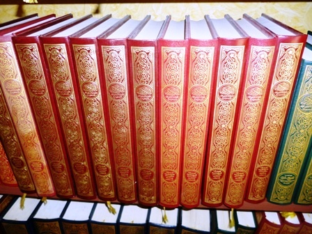 a row of red books sit on top of a desk