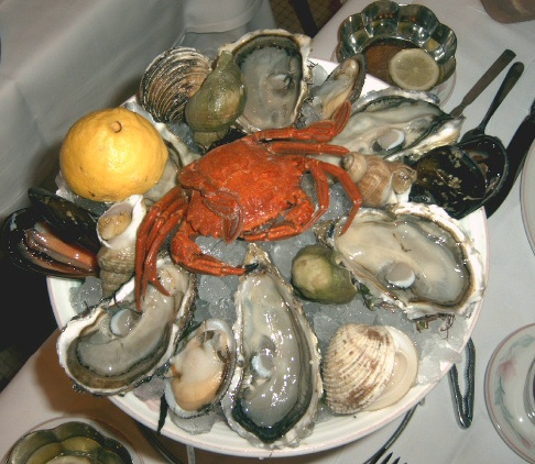 a plate of oysters, mussels, and clams sits on a table