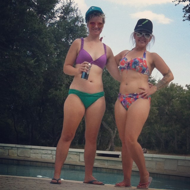 two women in bathing suits and hats standing by a pool