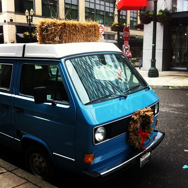 a blue van has a hay bale on top of it