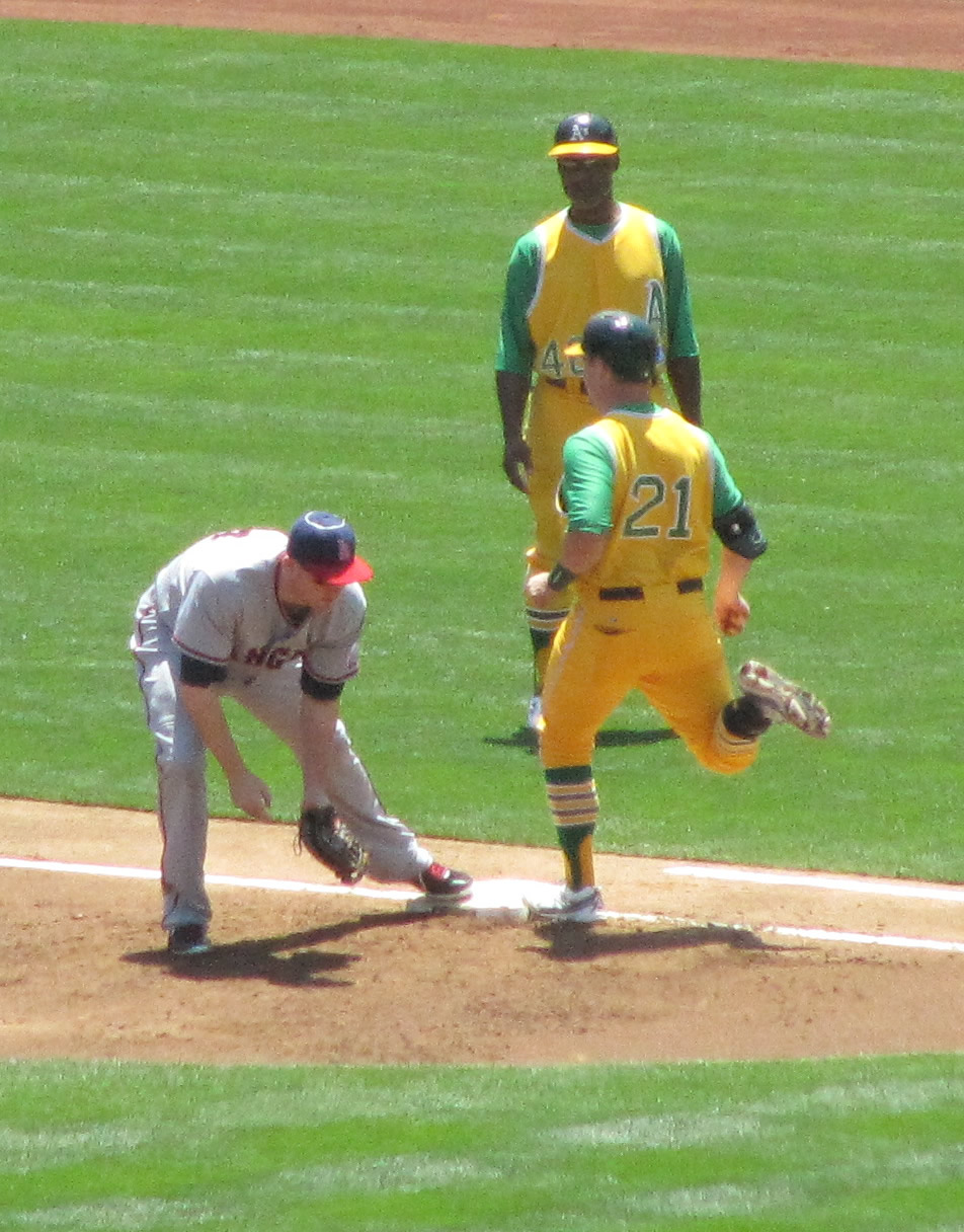 three men in yellow uniforms playing baseball with a baseball base