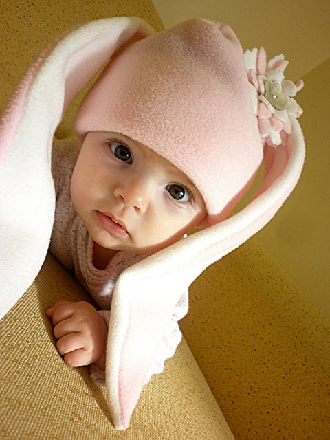 an adorable baby wrapped in a blanket wearing a bunny hat