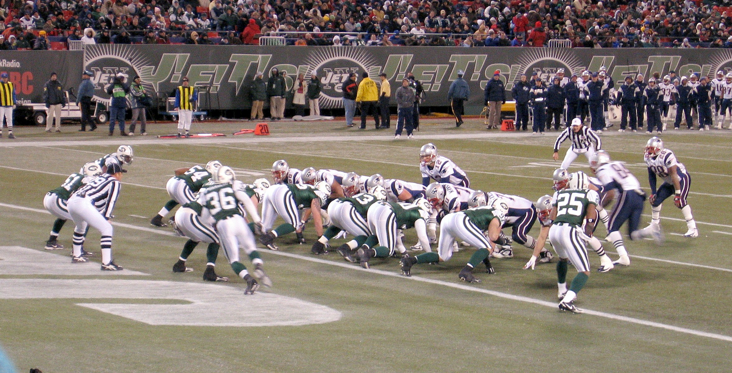 several american football players are in a line as a crowd watches from the stands