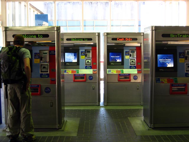 two people are standing near a line of atm machines