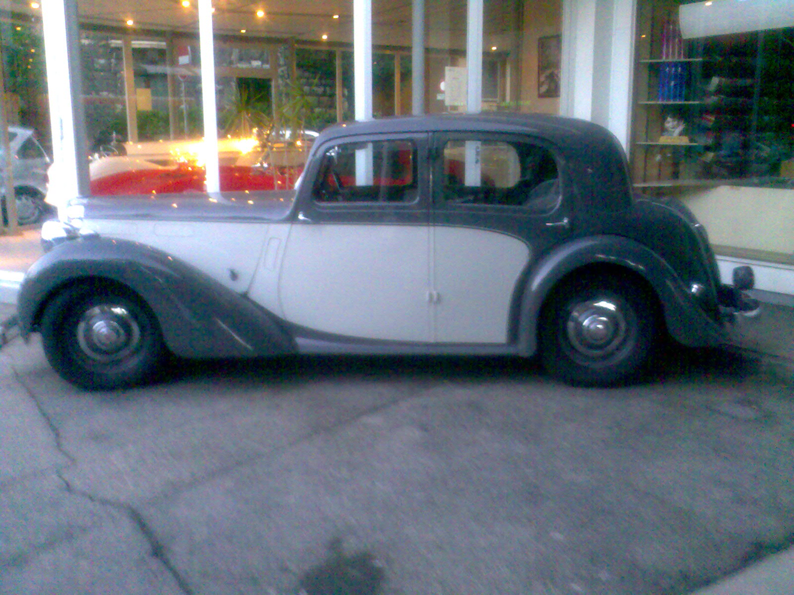 an antique black and white car parked outside of a store