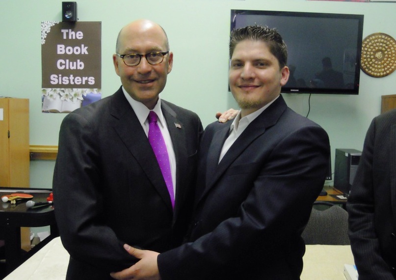 two men in business attire, one in suit and the other in purple tie