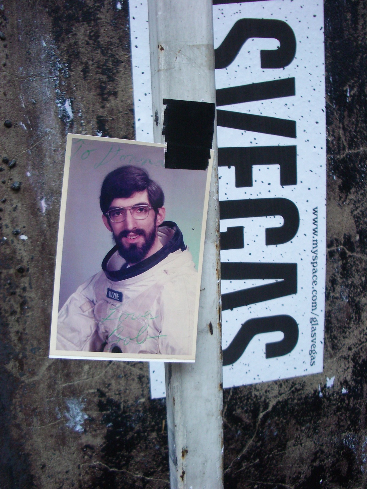 a picture of a man wearing glasses sits on a pole