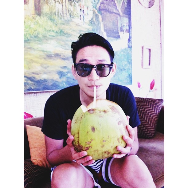 a man holding a green coconut drink in front of his face