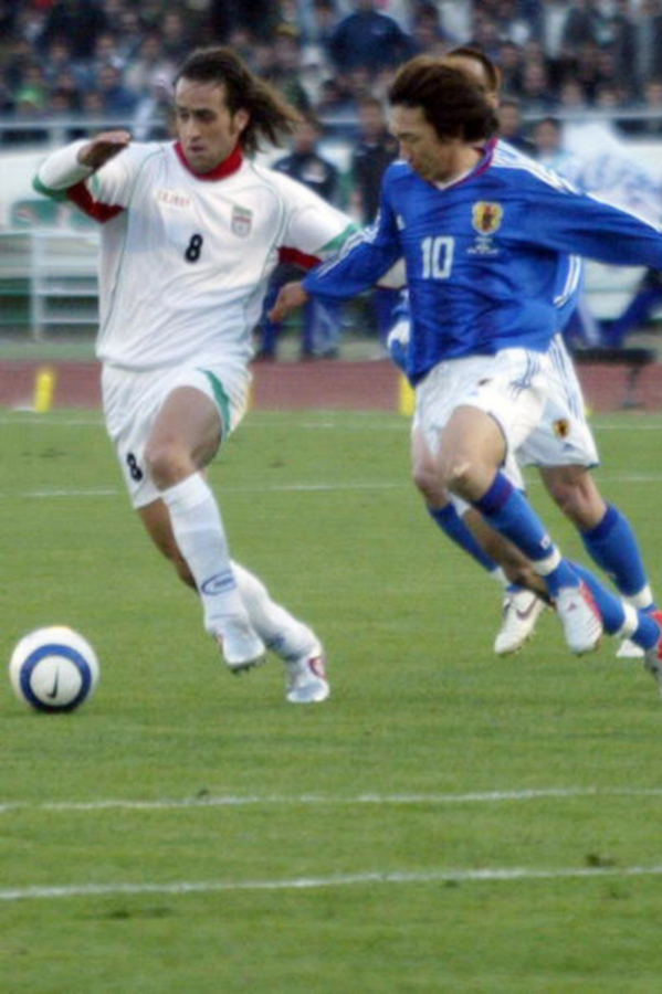 two men kicking soccer balls on a field