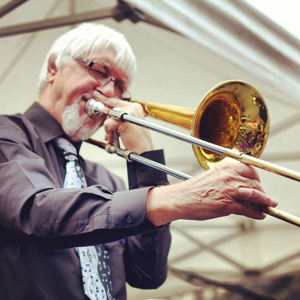 an older man playing the trumpet in front of other people