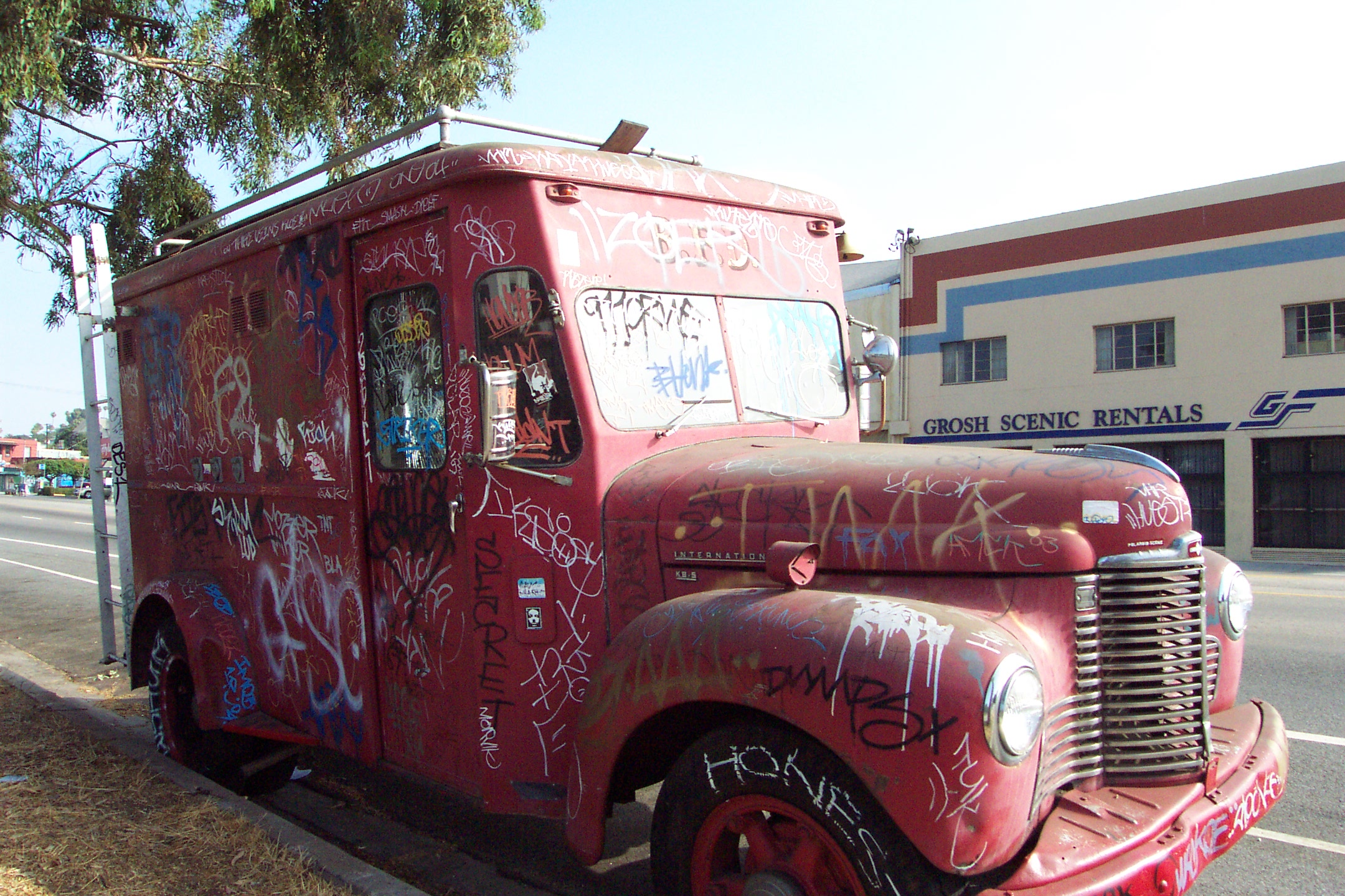 an old red truck that is sitting on the side of the street