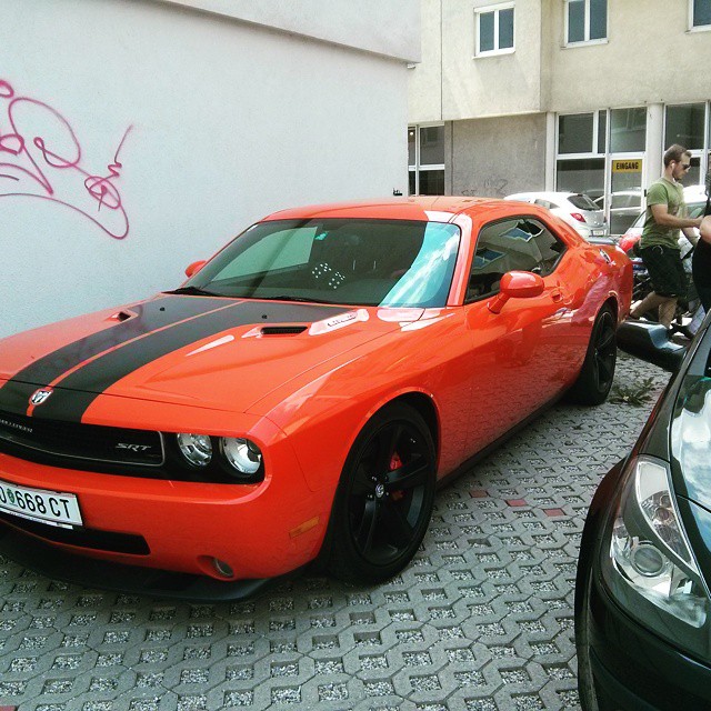 an orange car with a black stripe next to other cars
