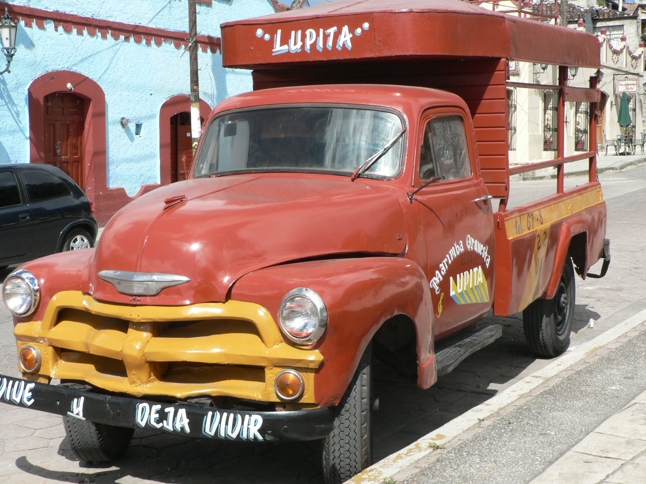 old rusty, red, orange pickup truck parked at curb