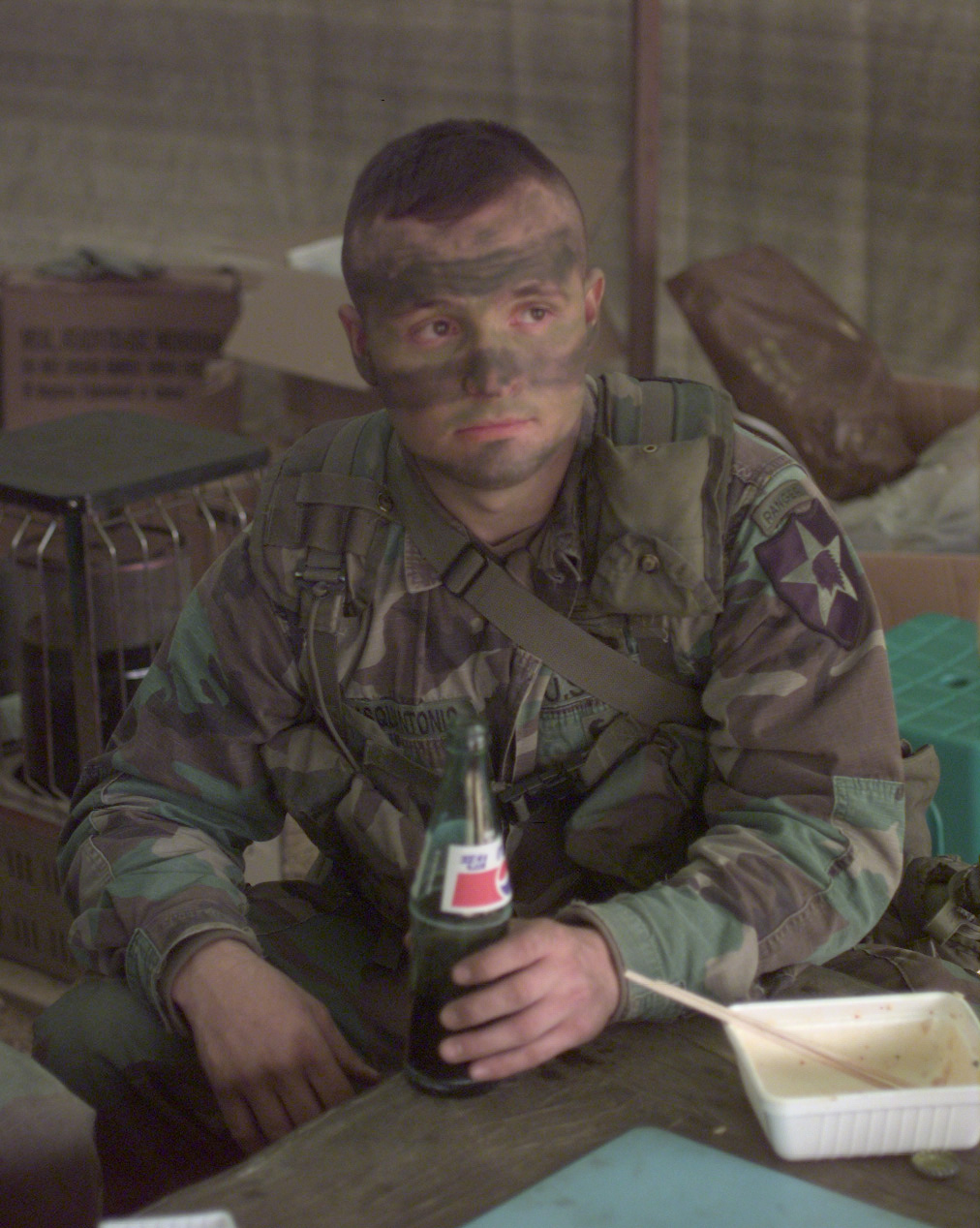 the soldier is sitting down holding a beer