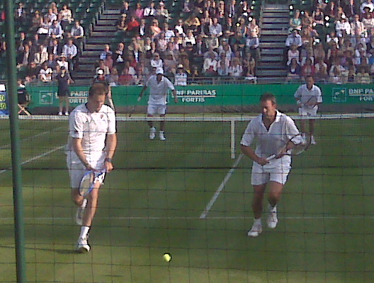 the men are playing tennis on the grass