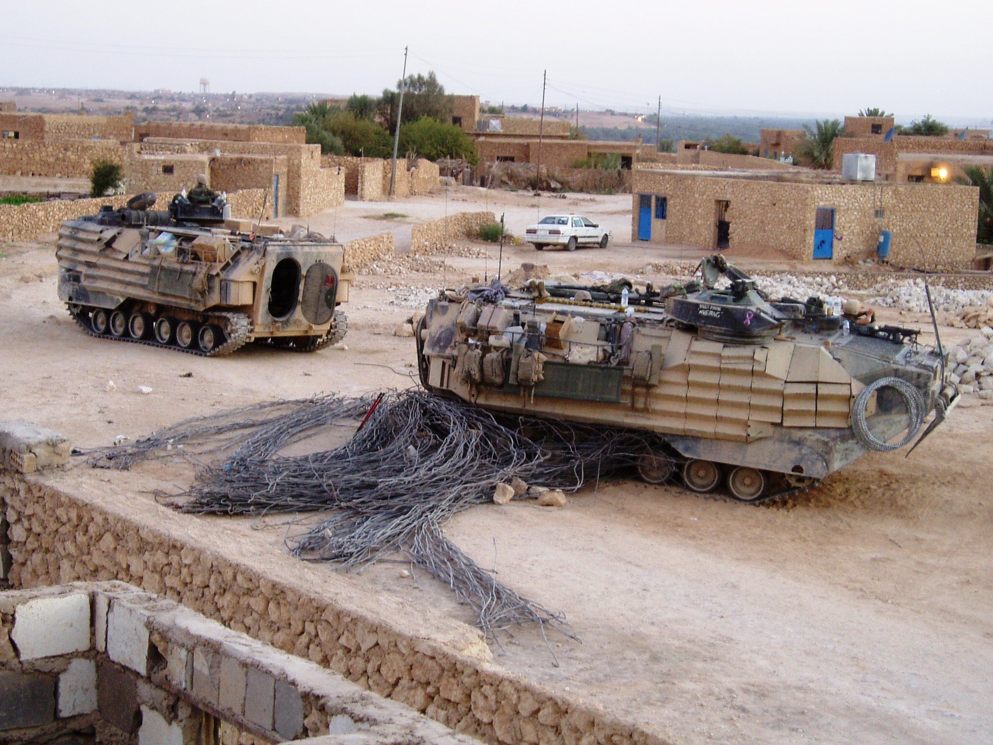 two army tanks parked in a dirt area