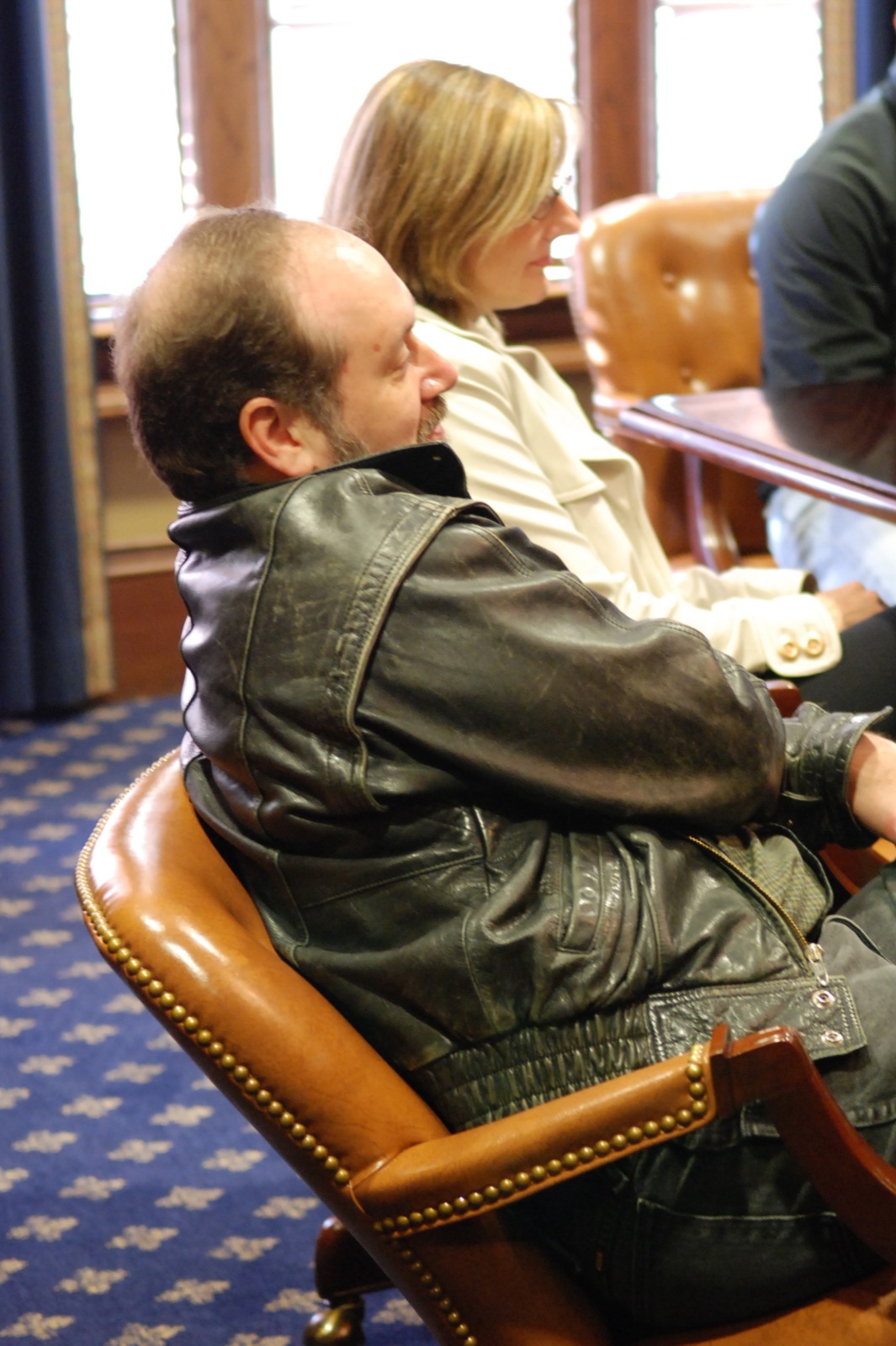 a man sitting in a brown leather chair looking towards the side