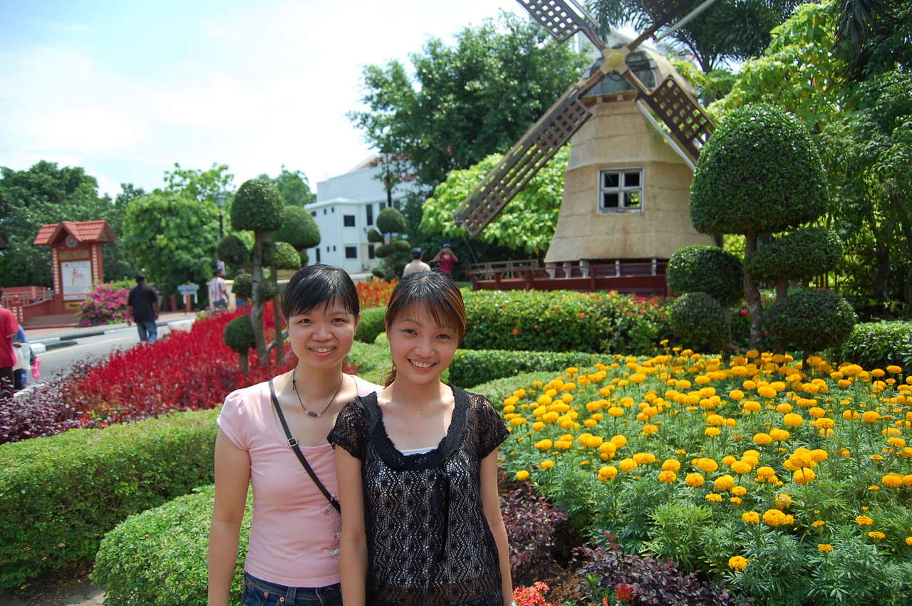 two women posing for a picture in front of a windmill shaped building