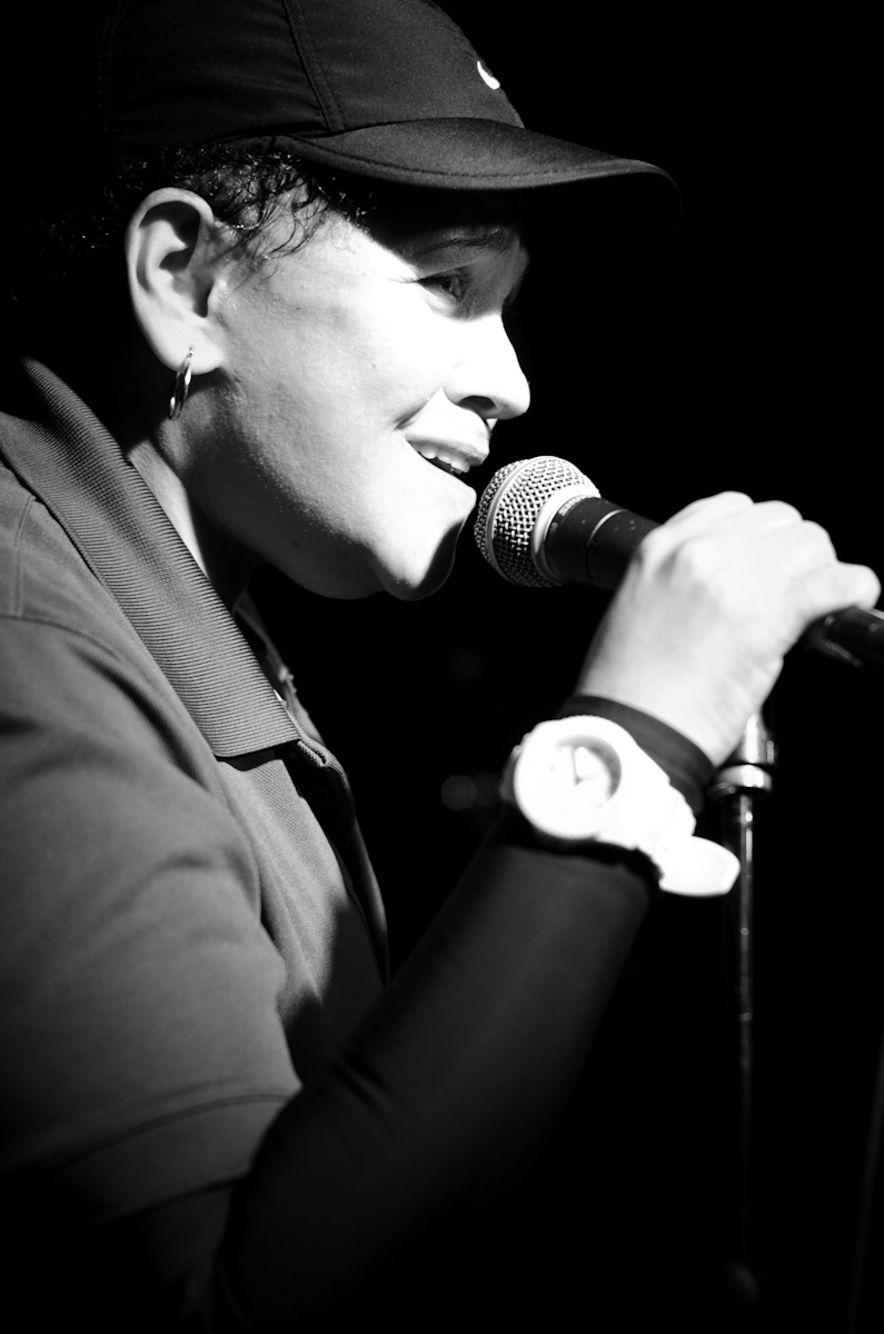 a woman in a hat on stage singing with a microphone