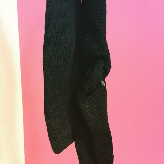 black tight socks hanging up against a pink wall