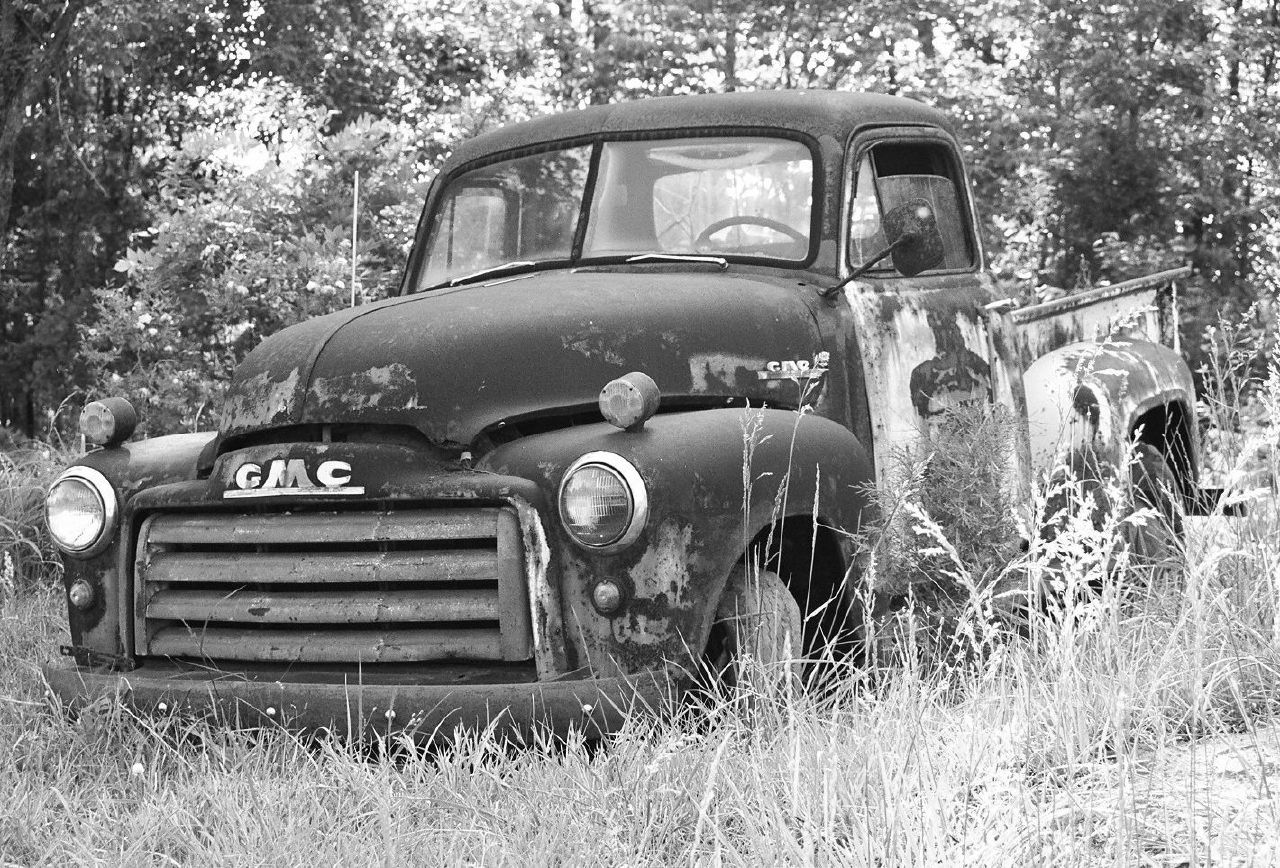 an old truck is parked in some grass