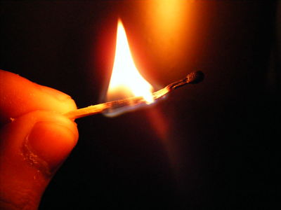 someone holds a lit match lighter in the dark