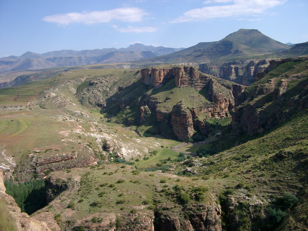 a valley surrounded by mountain formations on a bright sunny day