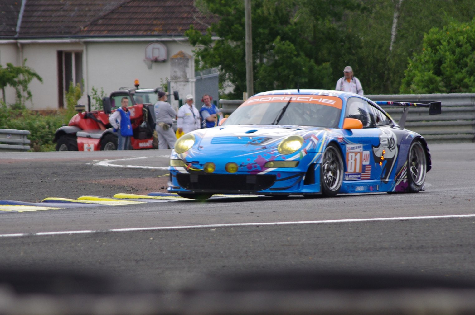 a racing car driving down the road near spectators