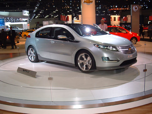 a small silver car on display at a convention
