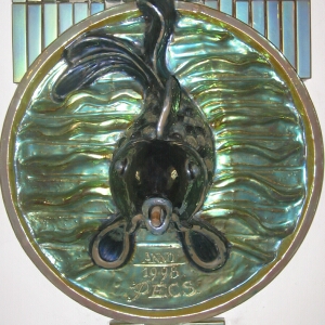 a wall mounted art glass duck holding scissors
