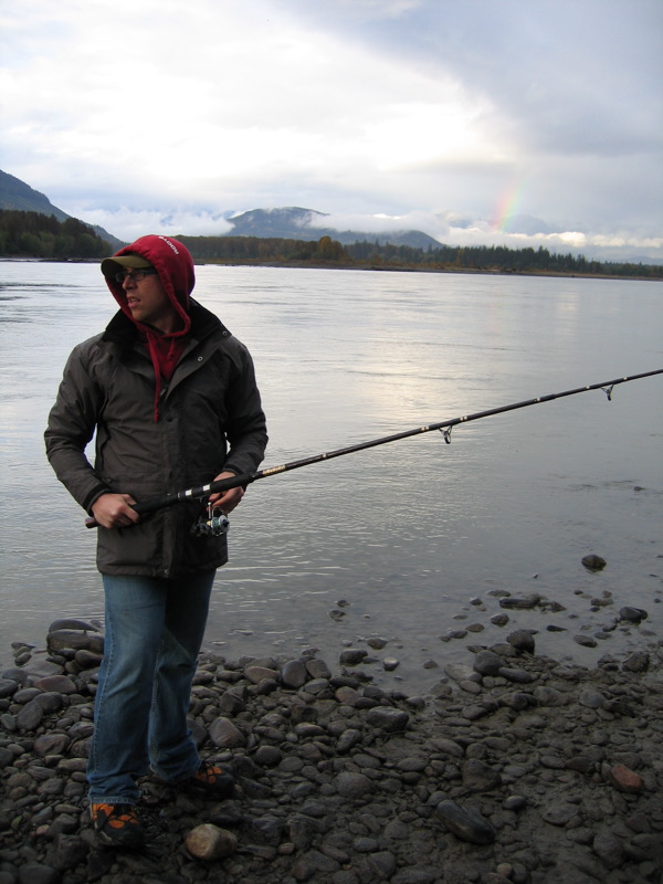 a man standing next to water holding a fishing rod