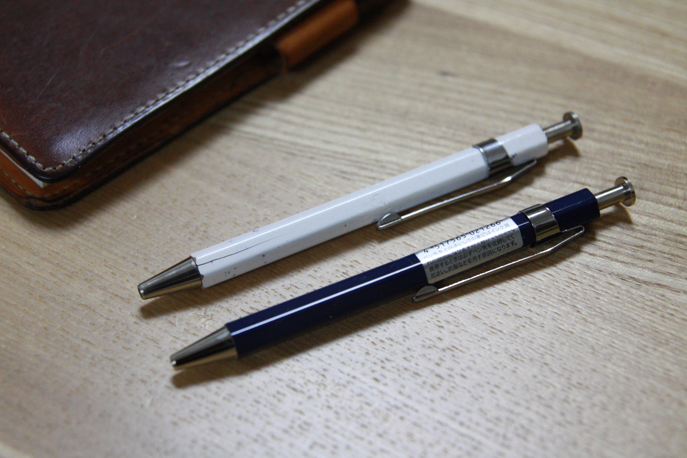 a close up of two pens on a table near a notebook